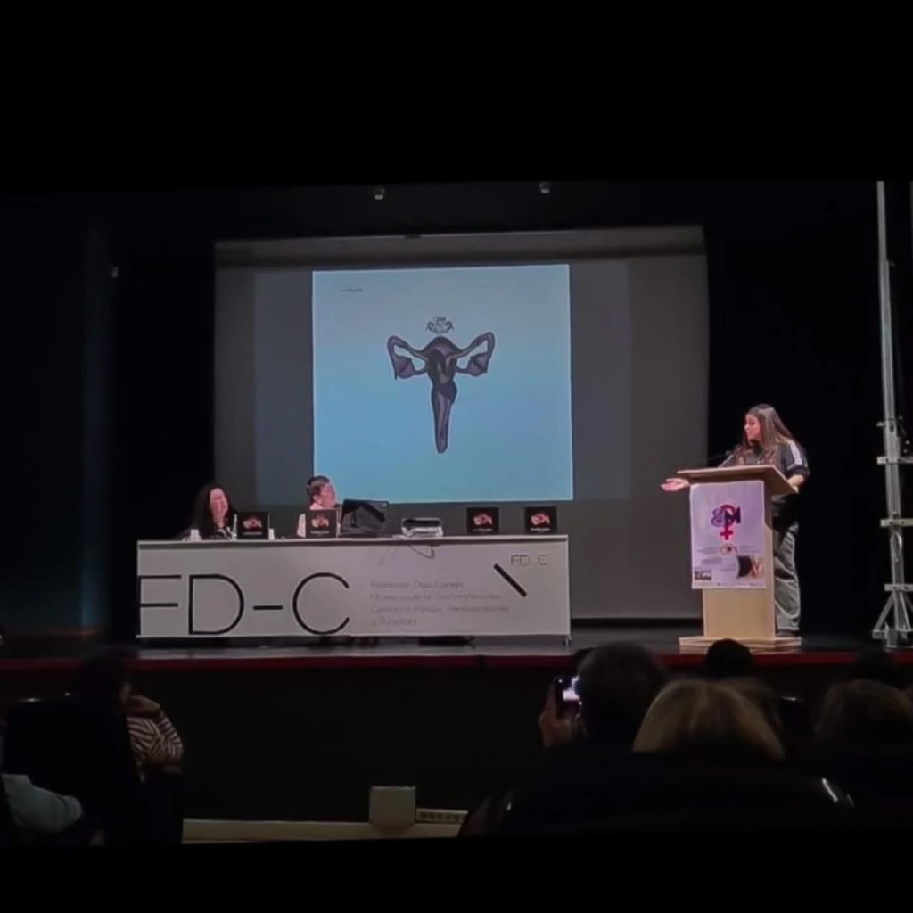 Mesa presidencial del acto de presentación en la Fundación Díaz-Caneja. Dos mujeres coordinan la sesión con ejemplares del libro. La pantalla muestra la palabra Antología.